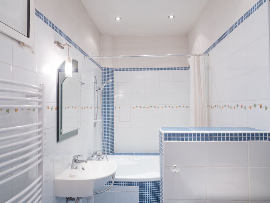 Clean shared bathroom with shower (bathtube), sink, toilet and washing machine