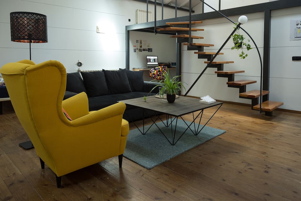 Main living room/space equipped with a double bed, sofa, chairs, huge table and TV.