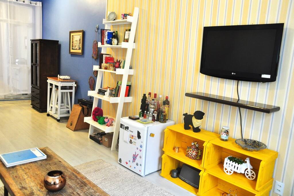 Frigobar disponível para uso, TV, decorações e móveis úteis na sala.