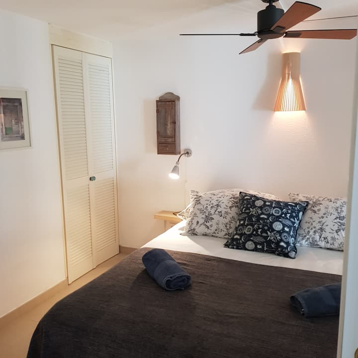 سرير مزدوج في غرفة النوم 2 مع مكيف هواء ومروحة سقف، في الطابق السفلي. الأبواب المنزلقة تفصل الغرفة نحو السلالم والسرير الفردي 