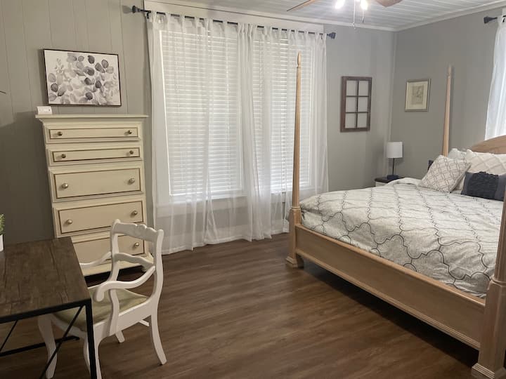 Spacious bedroom with king size bed,dresser with for clothes storage, and desk for workspace. 