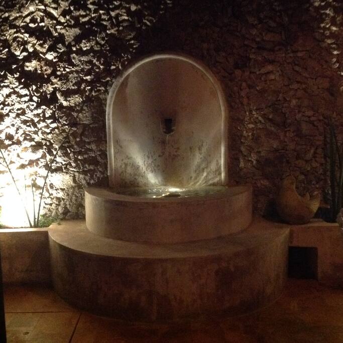 Interior patio at night with flickering lights from the fountain