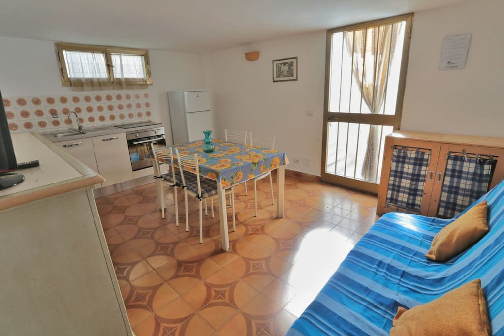 La porta d'ingresso è a vetri, fuori c'è sia una tenda parasole che una tettoia. Per accedere all'appartamento c'è una rampa di scale da scendere.
