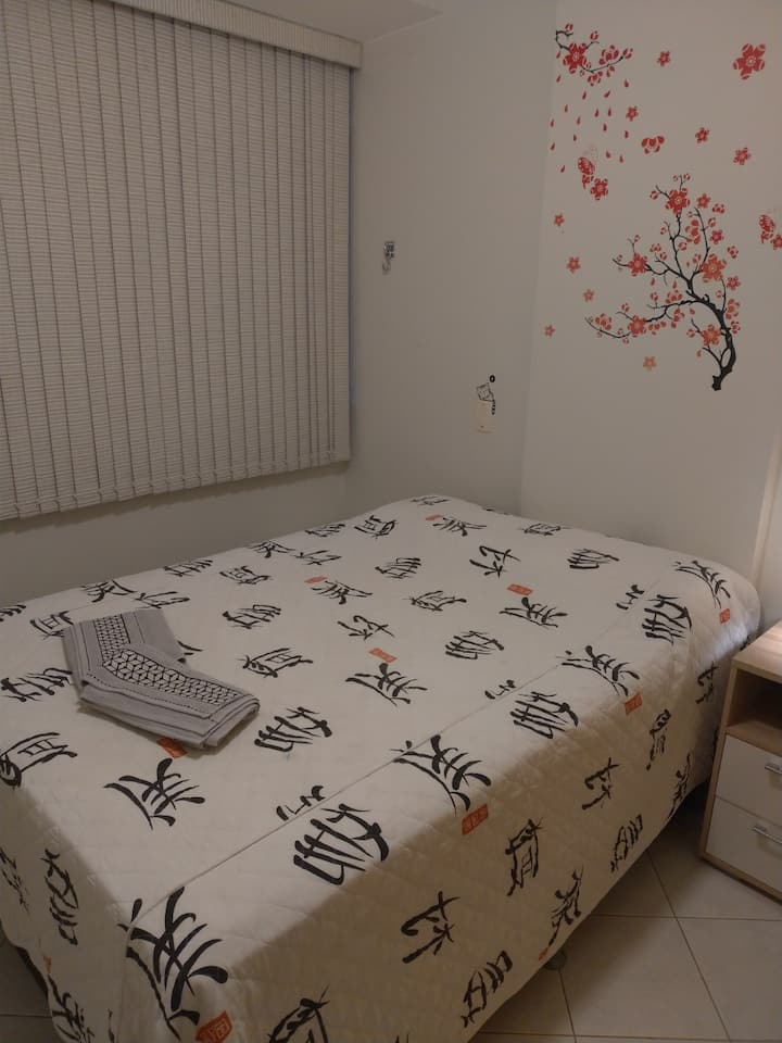 ห้องนอนที่ 2 พร้อมเตียงควีนไซส์ตู้ไม้แขวนเสื้อมู่ลี่ตาข่ายนิรภัยที่หน้าต่างและพัดลมเพดาน ผ้าปูที่นอนและผ้าขนหนู