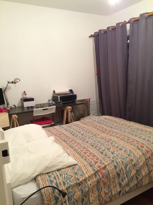 Une chambre avec lit 2 places et un grand bureau ainsi qu'un espace réservé dans le dressing.