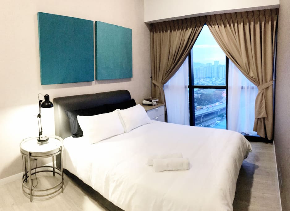 A bedroom with a queen sized bed & plush pillows.