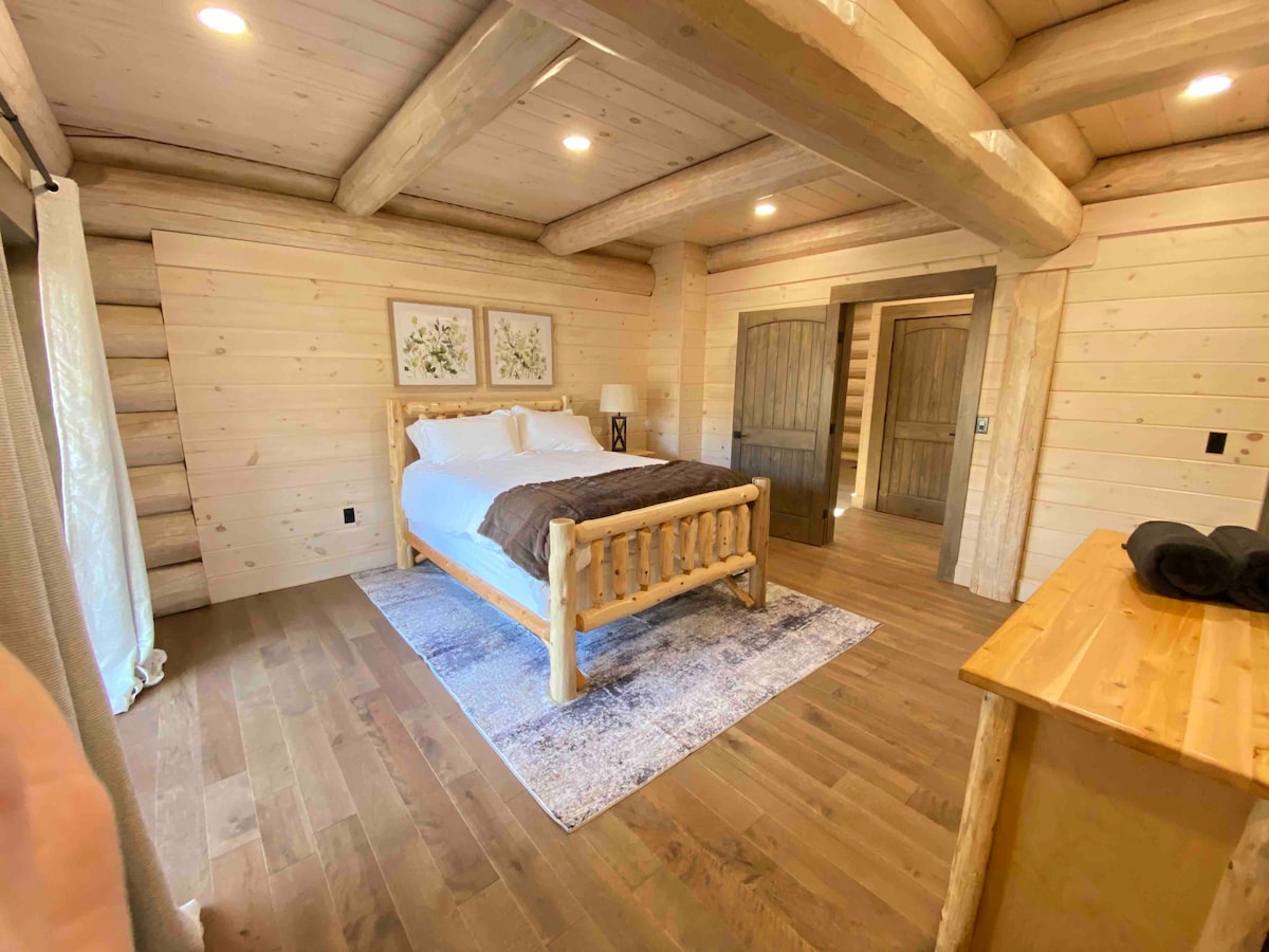 غرفة النوم الرئيسية في الطابق الأول تتميز ببياضات ناعمة ومظهر الكوخ المريح، مع حمام رئيسي داخلي وخزانة ملابس