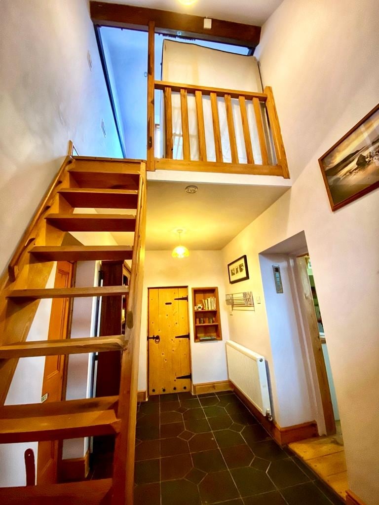 Le hall d'entrée, les marches raides jusqu'à la chambre du loft, la porte devant la salle de bain, à droite du salon principal