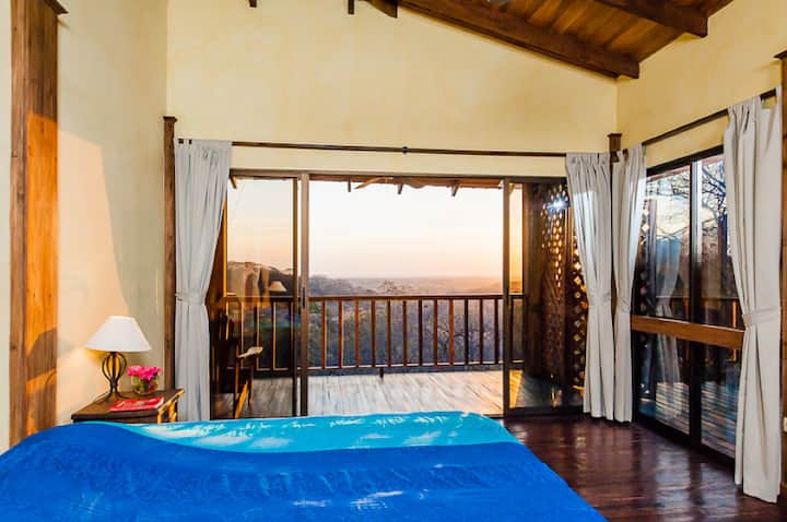 Quarto principal com cama king size com vista para a floresta, o mar e a piscina. Armário no banheiro deste quarto.