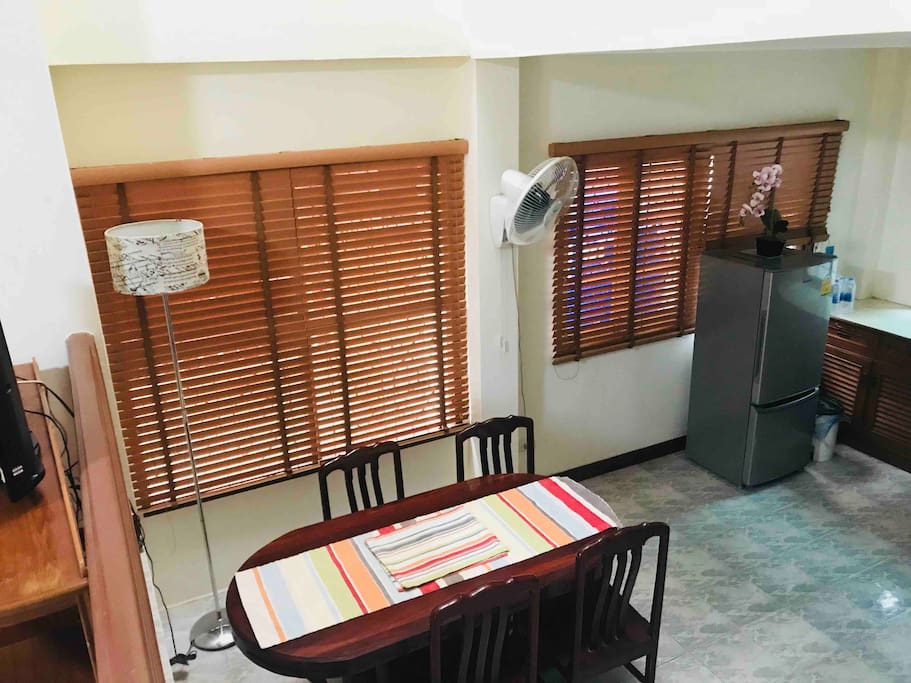 Dining table in a big space of kitchen area plus a refrigerator