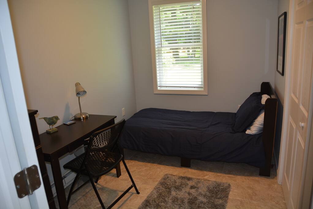 Bedroom with very comfortable bed, table and chair, and dresser, plus a lighted closet.