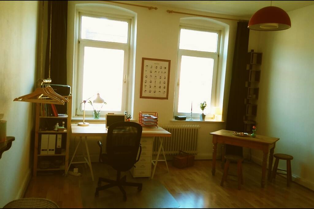 sunny and spacious room with a desk, a place to store your luggage in and a little table.