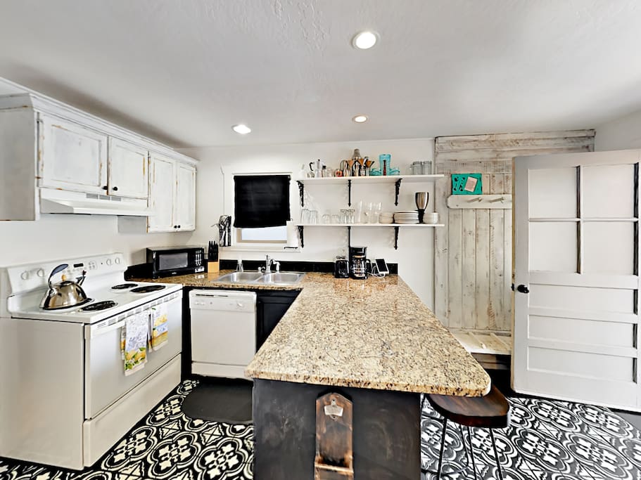 The updated kitchen is fully stocked with dishes, glasses, and cookware.