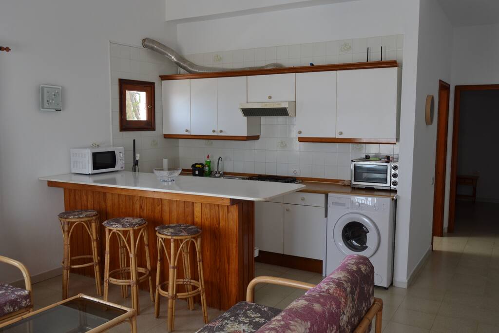 cocina equipada con lavadora, microondas, vitro de gas, y todo el menaje necesario