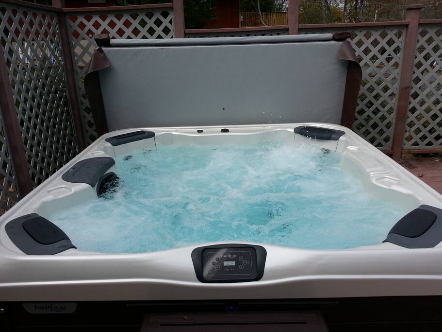 Relaxing hot tub under the stars wth easy movable protective cover resting behind,