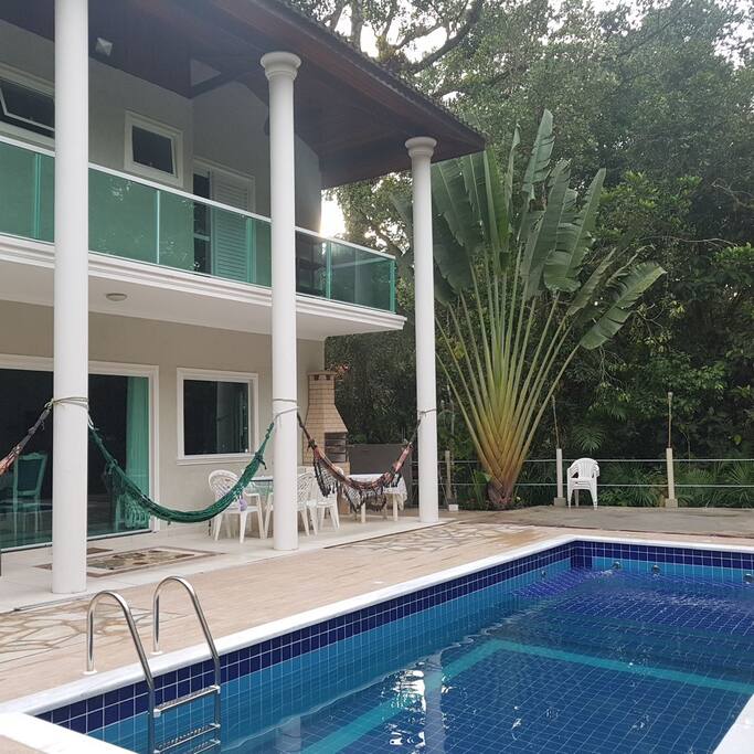 Piscina de frente para a varanda com redes, rodeada pela Atlântica