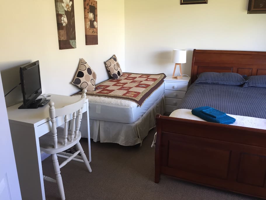A large bedroom which contains a queen size bed, a single bed, another fold down from the wall single bed, which is really only recommended for children probably under 12 or not to tall or over 55kg. I don't have a cot, sorry. It Also has a desk and another tv.