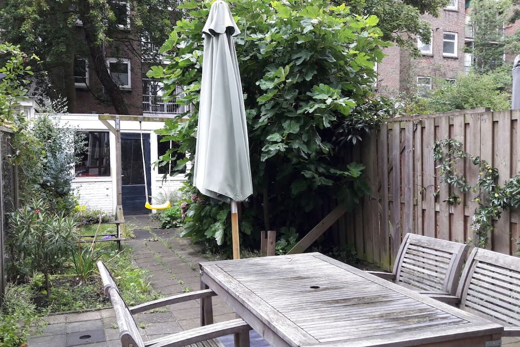 Sunny garden includes gardenfurniture, parasol and swing.