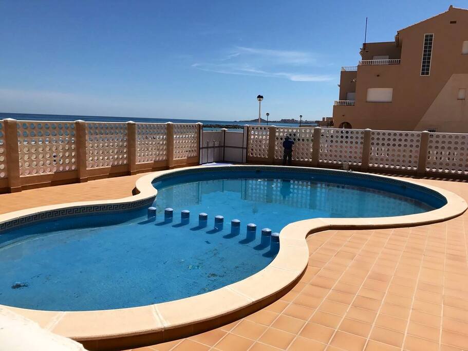 El apartamento cuenta con piscina comunitaria en primera línea de playa, ideal para quitarse la sal y la arena antes de volver a casa