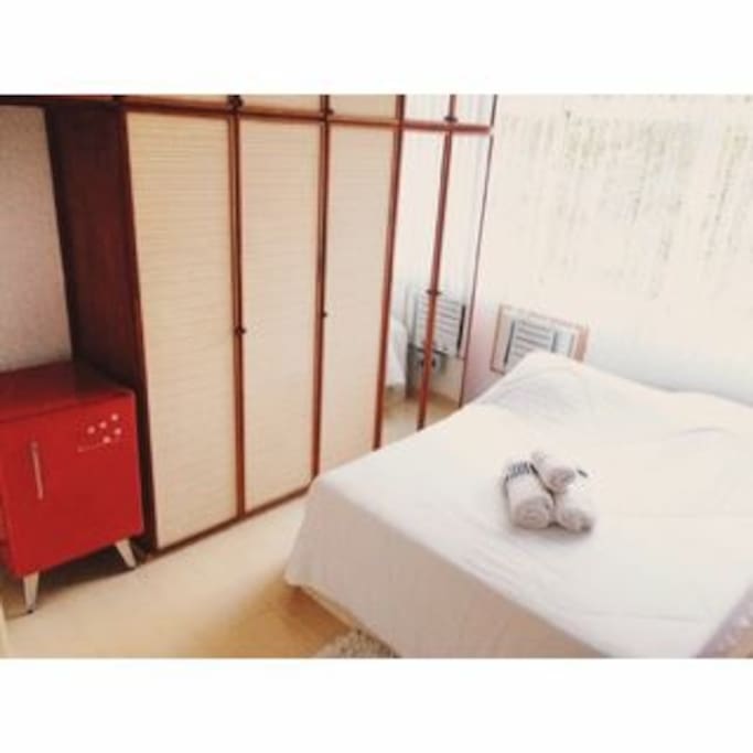 Quarto com uma cama de casal, frigobar, TV LCD, armário com cabides.