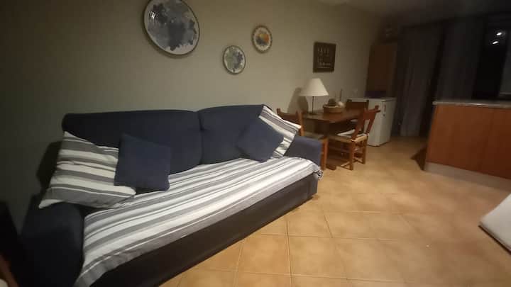 客厅的沙发床，配有小厨房的餐桌和阳台，以及通往露台的门