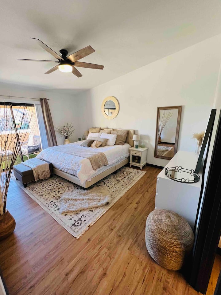 ห้องนอนใหญ่พร้อมที่นอนไฮบริดหรูหราขนาดคิงไซส์  ห้องนอนมีห้องน้ำในตัวและยังมีลานระเบียงพร้อมประตูบานเลื่อนด้านนอกที่มีหญ้าเทียมและที่นั่งม้านั่งพร้อมโต๊ะกาแฟ