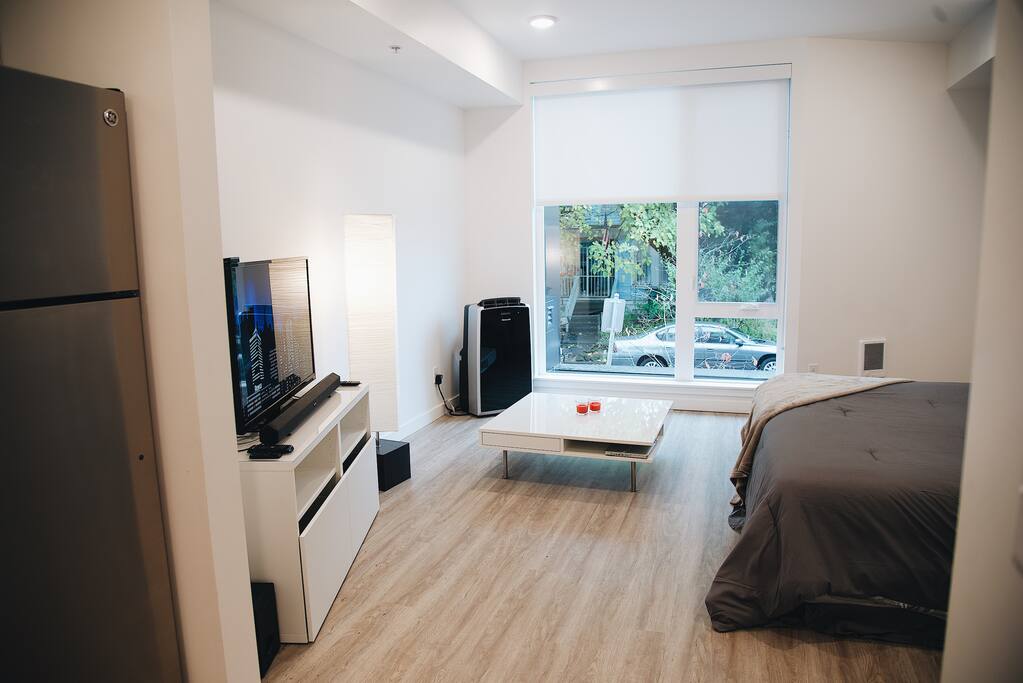 Open living area with a comfortable king size bed and soft linen a low profile coffee table and entertainment center with 42” TV all overlooking the busy streets and biking corridor of South East Portland.