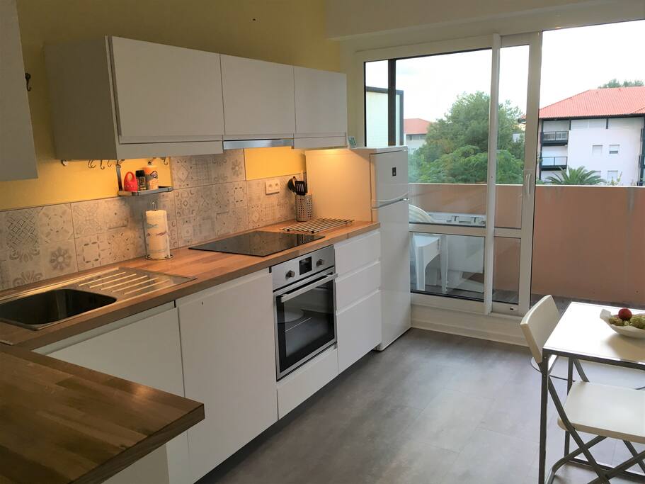 Cuisine équipée avec balcon filant, vue sur jardin