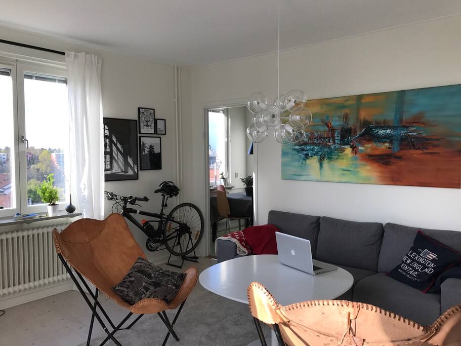 Living room connects to hall and kitchen. Big sofa, table and window towards Stora Essingen.