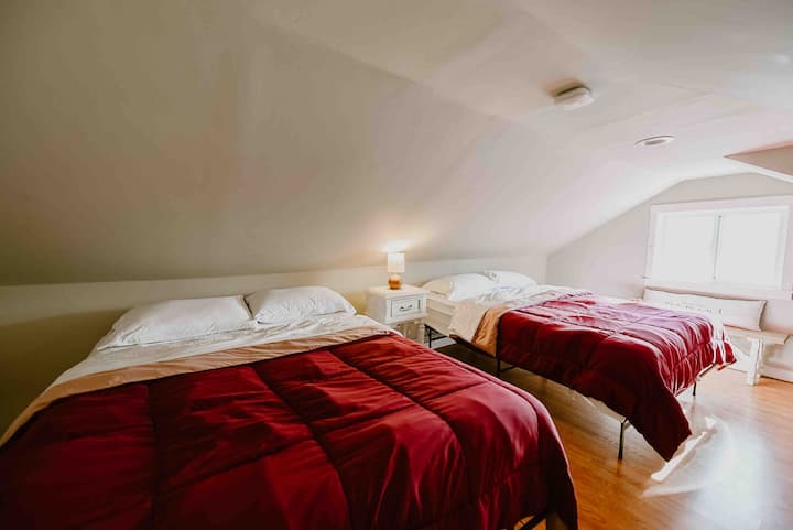 Relájate y desconecta en la acogedora zona loft, amueblada con dos cómodas camas de tamaño completo. Los techos suavemente inclinados y el ambiente tranquilo lo convierten en un refugio perfecto, que ofrece unas vistas impresionantes de la naturaleza circundante a través de la ventana cercana.