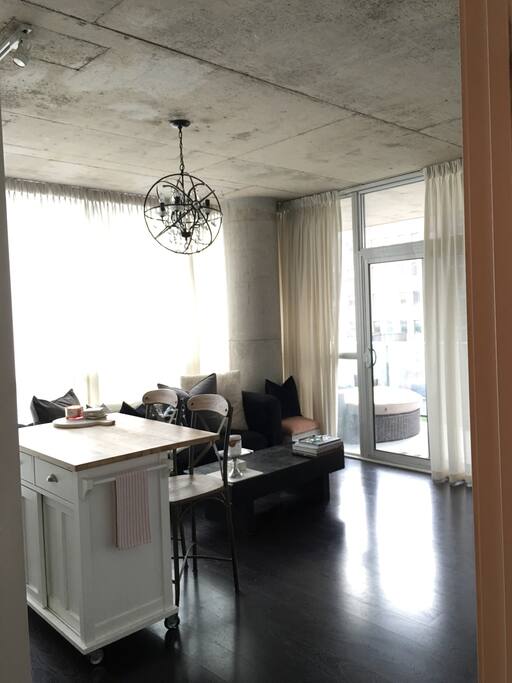 Open concept kitchen/living area with access to outdoor patio with large daybed for lounging.