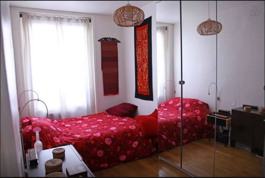 A room with a double bed, a desk and a big wardrobe