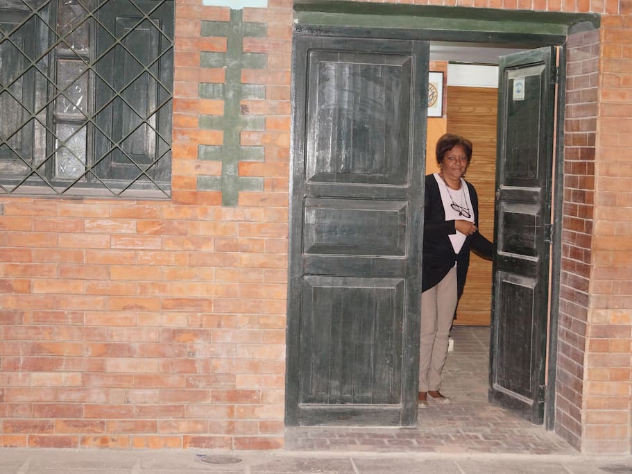 Entrada de la casa y la anfitriona lista para su llegada.