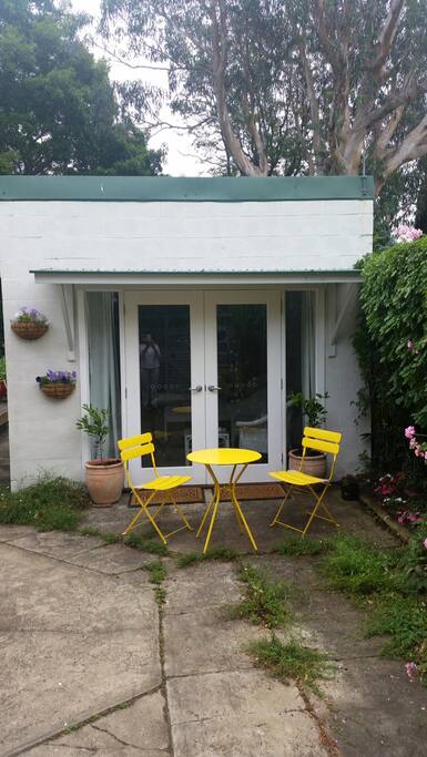 From the outside looking in! French doors opening into the court yard. Table and chair for your morning coffee in the sun.
