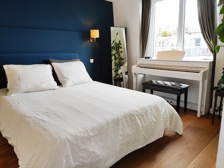 Krevat dopio "queen" në dhomën kryesore të gjumit të përmbytur nga dielli.