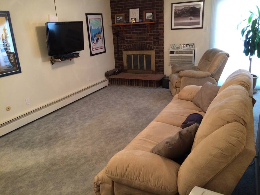 Living room with 40" flat screen TV, double reclining couch, recliner, AC unit and a functioning fire place