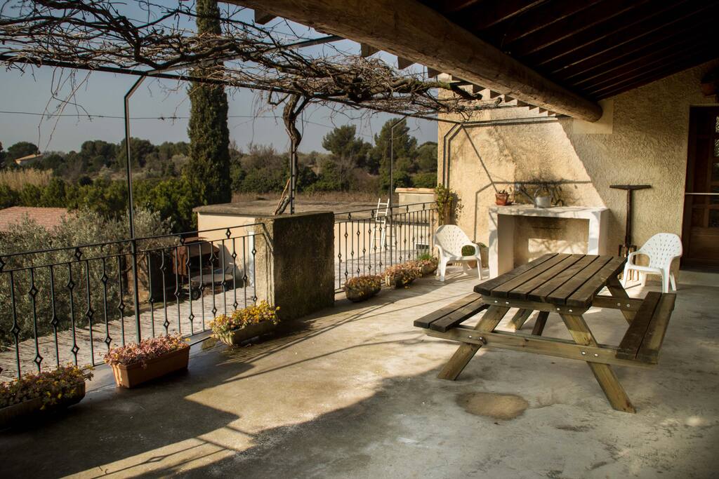Grande terrasse fermée par un portillon, ombragée et équipée avec plancha.