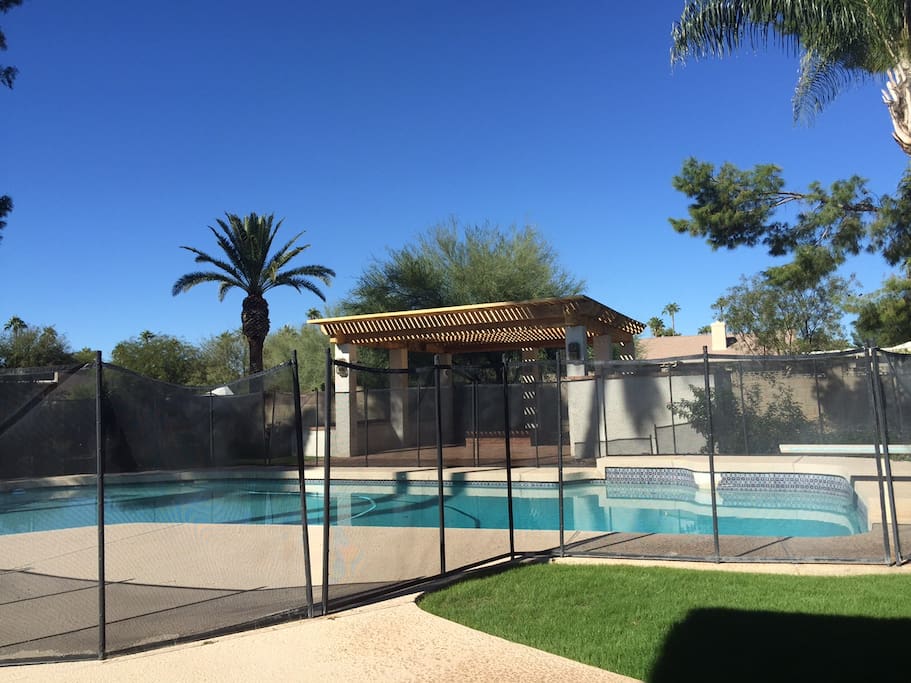Diving pool, gazebo w/ fire pit, child safety fence, green grass.