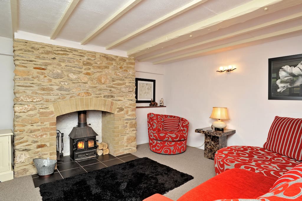 Lounge room with large comfy sofa, tv DVD player and log burner.