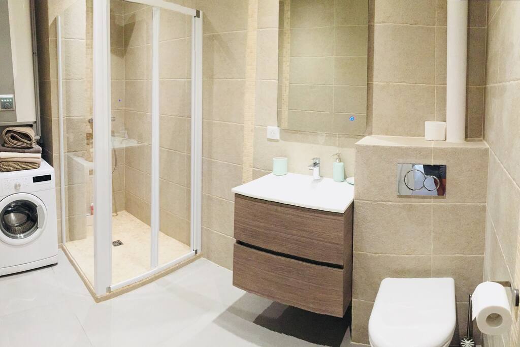 Salle de bain avec douche / machine à laver / toilette et meuble vasque