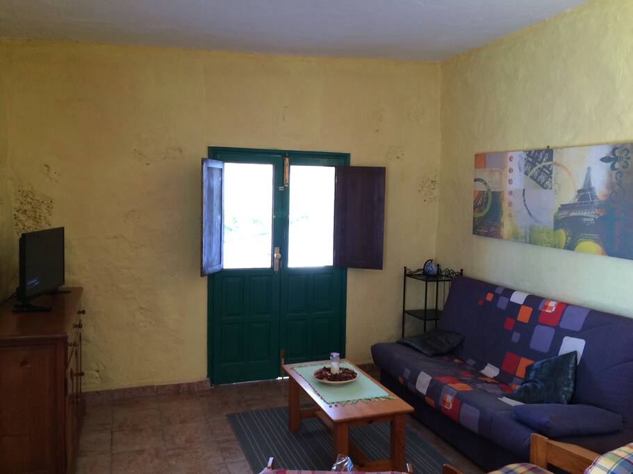 Salón con sofá cama y televisión.