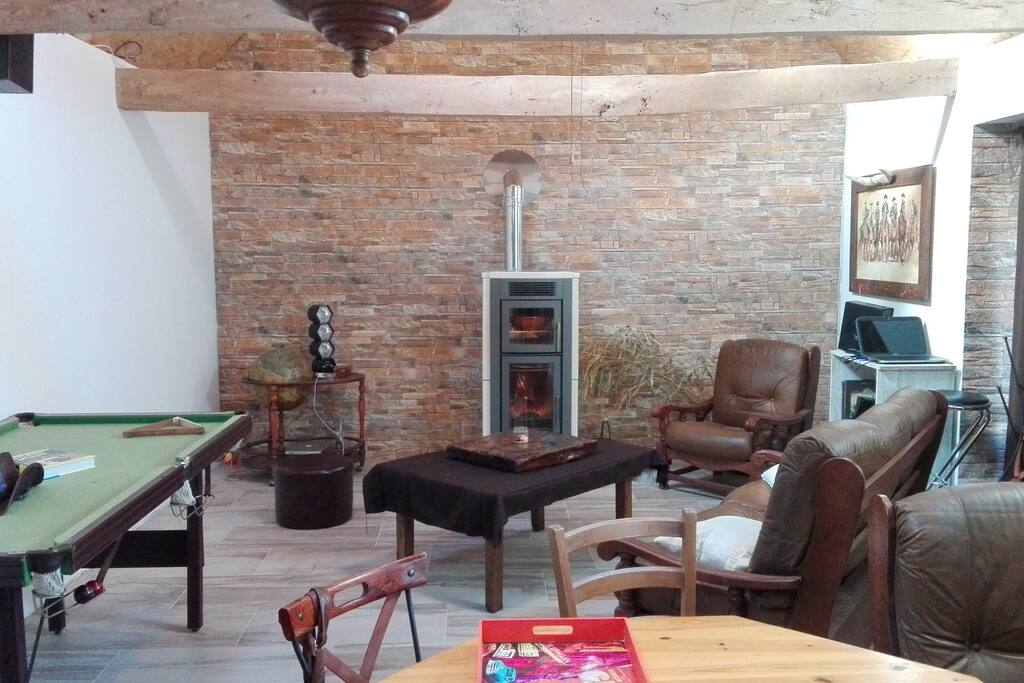 Le salon au décor un peu rustique avec un billard, un poele, ou encore un rétro-projecteur qui vous garantira une ambiance cocooning.