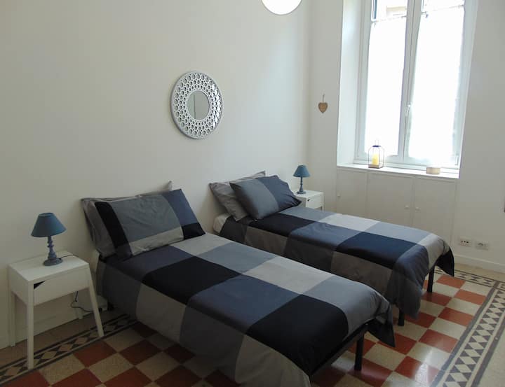 غرفة نوم ثانية تحتوي على سريرين مفردين وهيكل خزانة ملابس وطاولة بجانب السرير ومصابيح وطاولة.