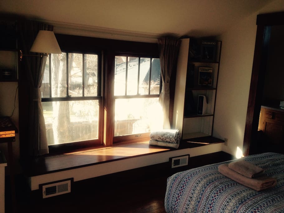 Sunny reading nook. Bookshelf to the right has vintage books about Colorado skiing, wilderness, and tourism, along with a magazine file filled with brochures from local attractions and a Colorado Springs visitor's guide.