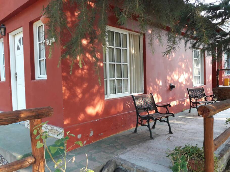 Chalet con cochera cubierta junto a la cabaña con veredon c bancos de jardin cubiertos de pinos