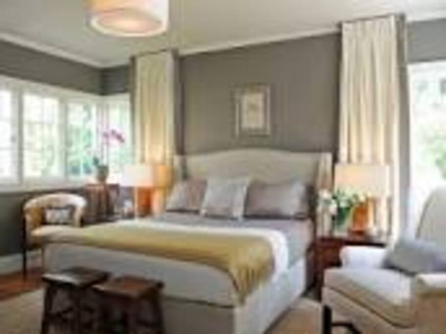 Very comfortable bed with sideboard and a chair.