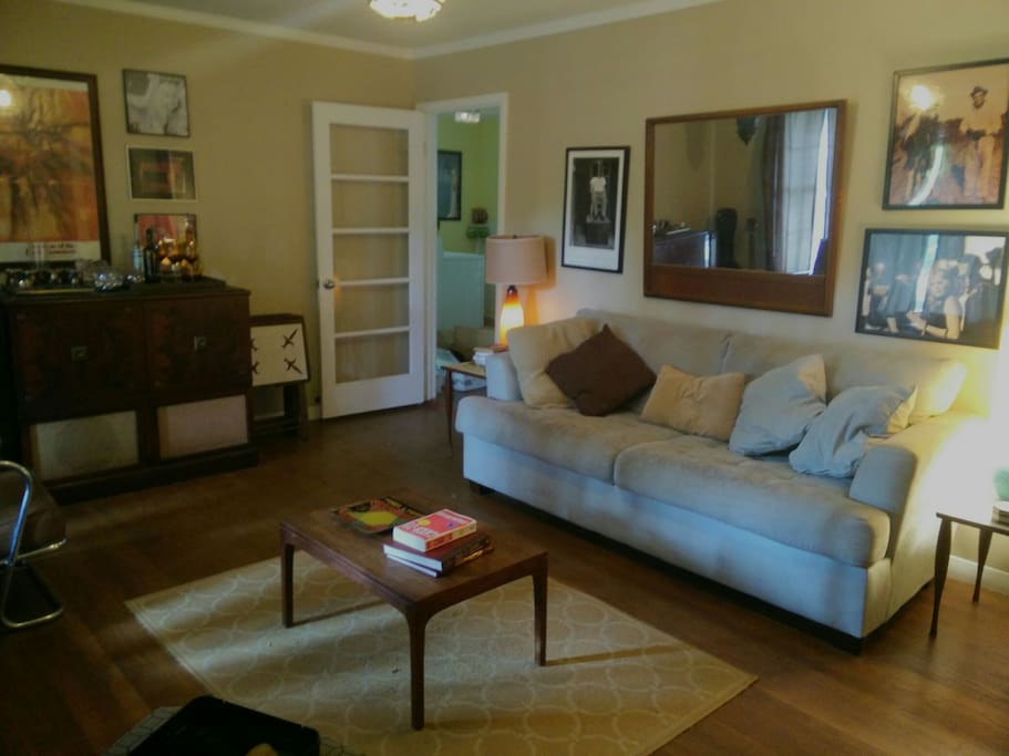 Mid century parlour room features a comfortable couch, two record players with vinyl collections and a wine and cocktail bar!
