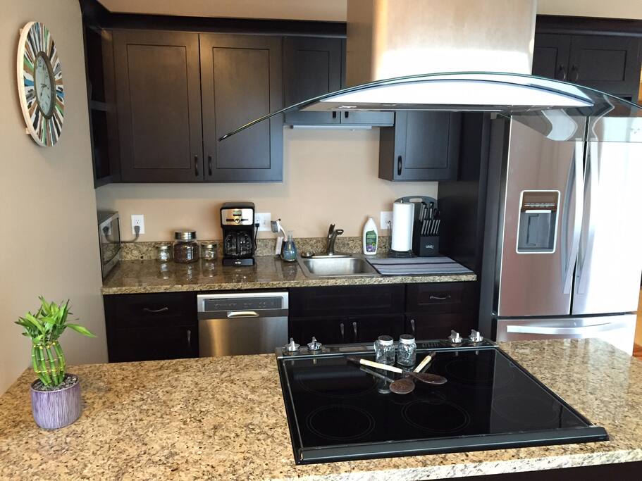 Kitchen with stove/oven, refrigerator, dishwasher, microwave, coffee maker, hood range, pots/pans, utensils.