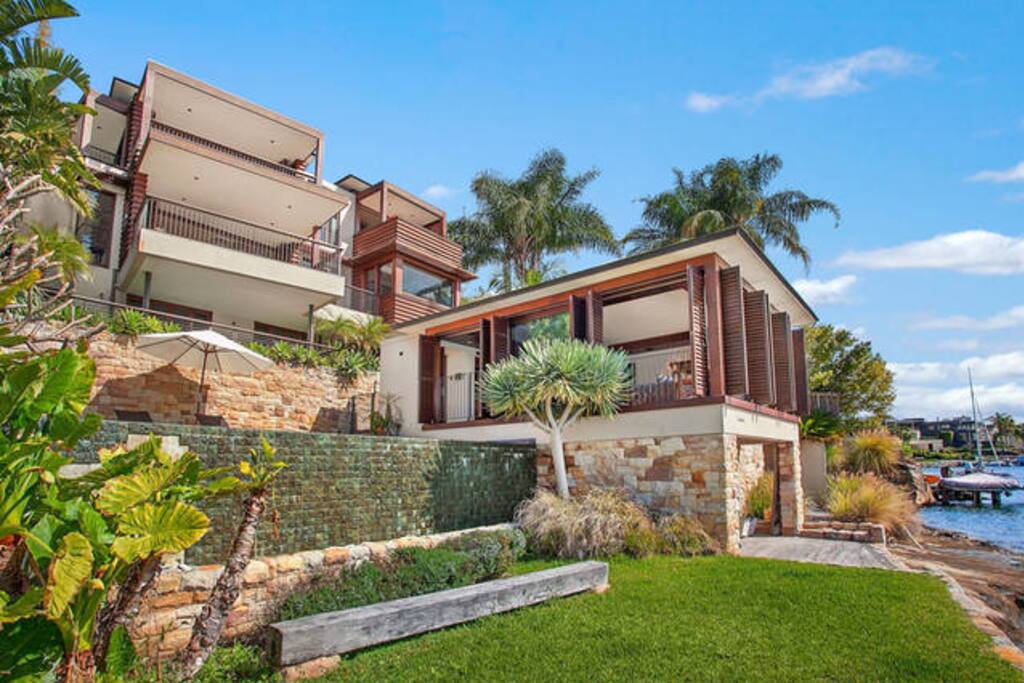 Your own private lawn with outdoor table and chairs for two. Boathouse underneath with kyaks and small boat. The floor to ceiling glass windows of your studio pool house open onto the harbour and pool