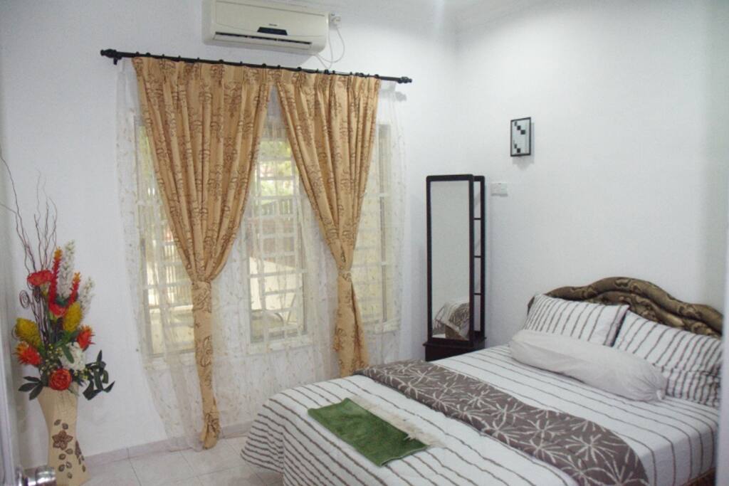 This is the master bedroom. it is complete with a queen size bed, a mirror, a cupboard, iron and iron board, a laundry basket, air conditioner and a bathroom.
